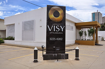 Fachada do Instituto VISY em Goiânia, com totem preto e o símbolo dourado